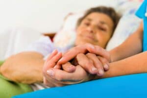 An old woman holding the hands of a caregiver